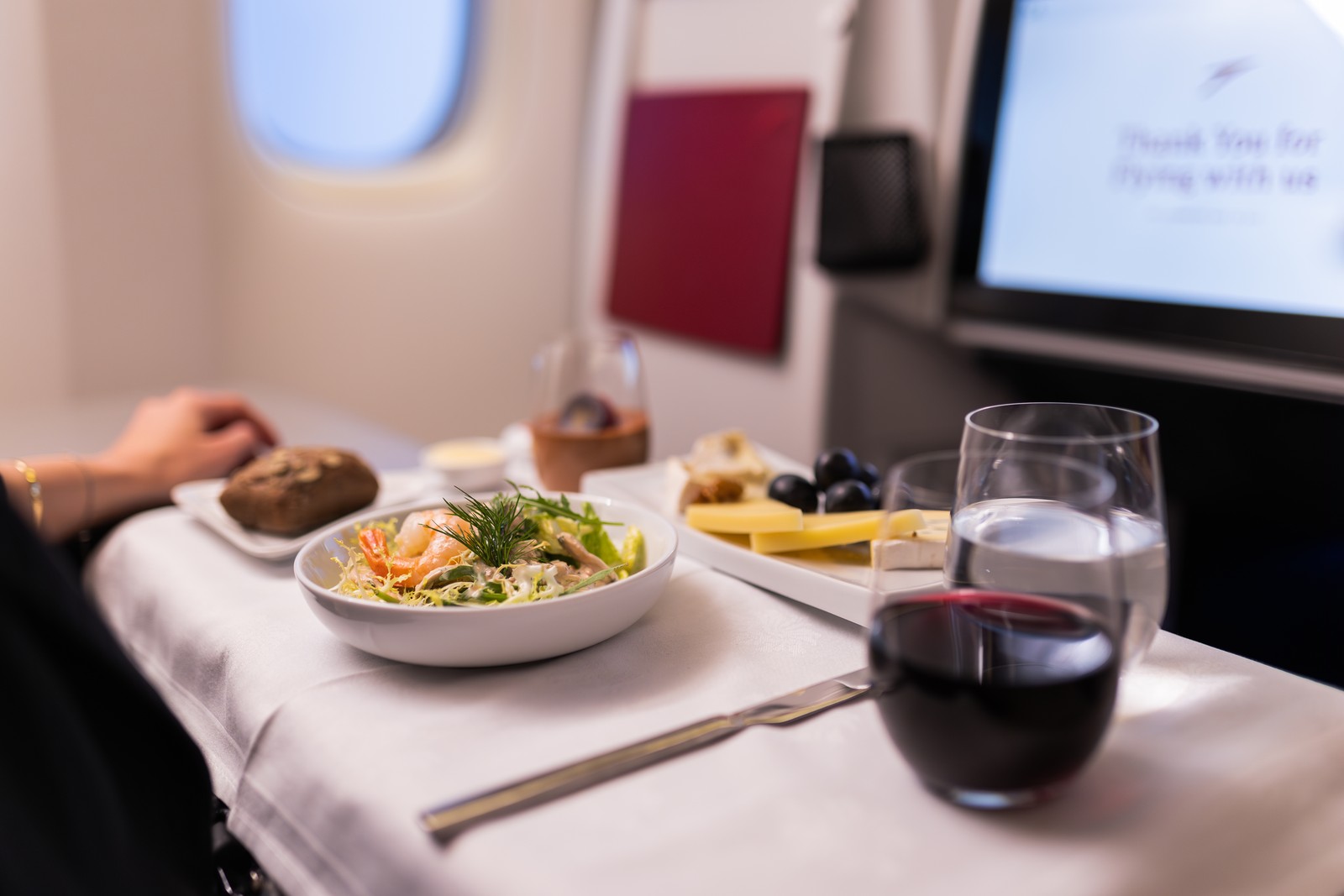 Fine dining experience in Austrian Airlines Business Class, featuring a freshly prepared meal and premium wine service. Photo by Austrian Airlines.