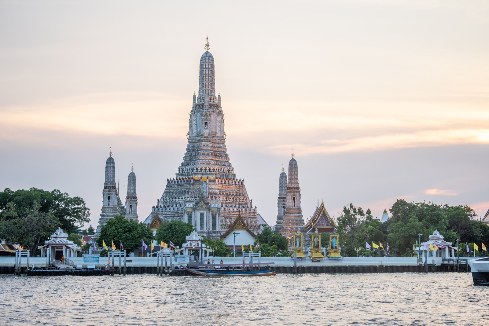 Sunset at Thailand’s iconic riverside Wat Arun temple glowing softly as the sun sets over the Chao Phraya River.
